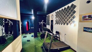 A gym with a treadmill, punching bag, and weight machines. - Lodging in the center with gym and parking included. (Loja)