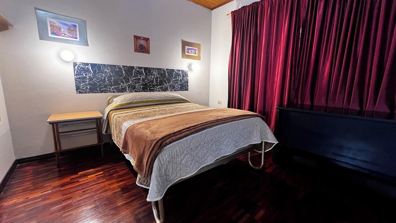 Una habitación de hotel con cama, mesita de noche y cabecera con diseño tipo mármol.