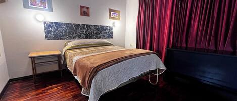 Una habitación de hotel con cama, mesita de noche y cabecera con diseño tipo mármol.