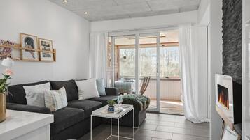 Un salon moderne avec un canapé gris foncé, une table basse blanche et une cheminée.