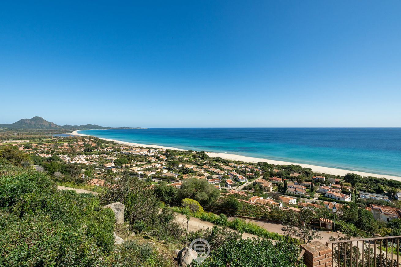 A coastal town with a beach, houses, and greenery.