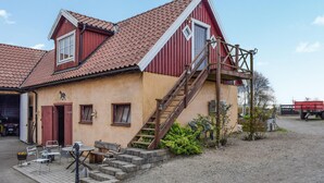 A two-story building with a red roof and beige walls, featuring a staircase leading to the upper floor. - Pet friendly apartment in Degeberga (Degeberga)