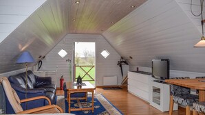A cozy attic room with a loft bed, a leather sofa, a small dining table, and a TV. - Pet friendly apartment in Degeberga (Degeberga)