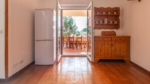 Una cocina con refrigerador, armarios de madera y vistas a un comedor exterior.
