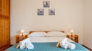 Una habitación de hotel con una cama, dos mesitas de noche, un armario de madera y tres cuadros colgados en la pared.