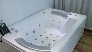 A modern spa bath with a control panel, a wooden floor, and a window with curtains. - Hotel Gran Real Punta Cana (Punta Cana)