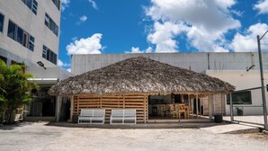 A building with a thatched roof structure, a fenced area with benches, and a clear sky. - Hotel Gran Real Punta Cana (Punta Cana)