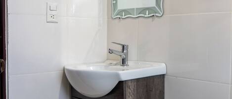 A bathroom with a white sink, wooden cabinet, and a mirror with a decorative frame.