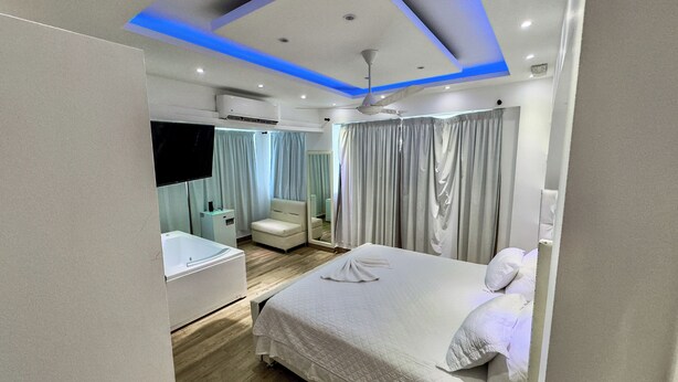 A modern bedroom with a bed, bedside table, and a mirror. - Hotel Gran Real Punta Cana (Punta Cana)