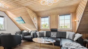 Ein moderner Loftraum mit einer gebogenen schwarzen Ledersofa, einem Holztisch und einem Gemälde an der schrägen Decke.