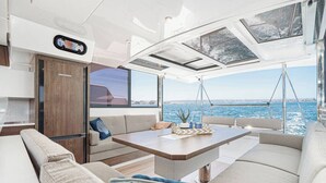 Das Interieur einer Yacht mit Essbereich, Sitzgelegenheiten und Blick auf das Meer.