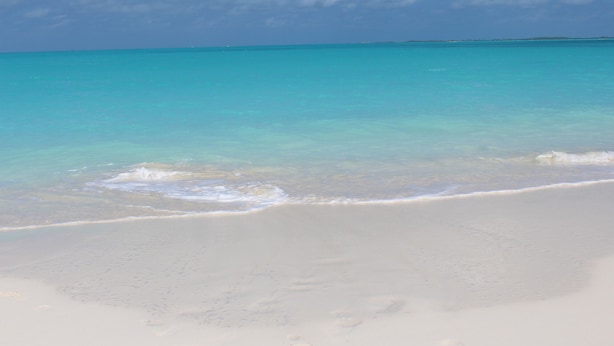 Ein Strand mit klarem türkisblauem Wasser und einem sandigen Ufer.