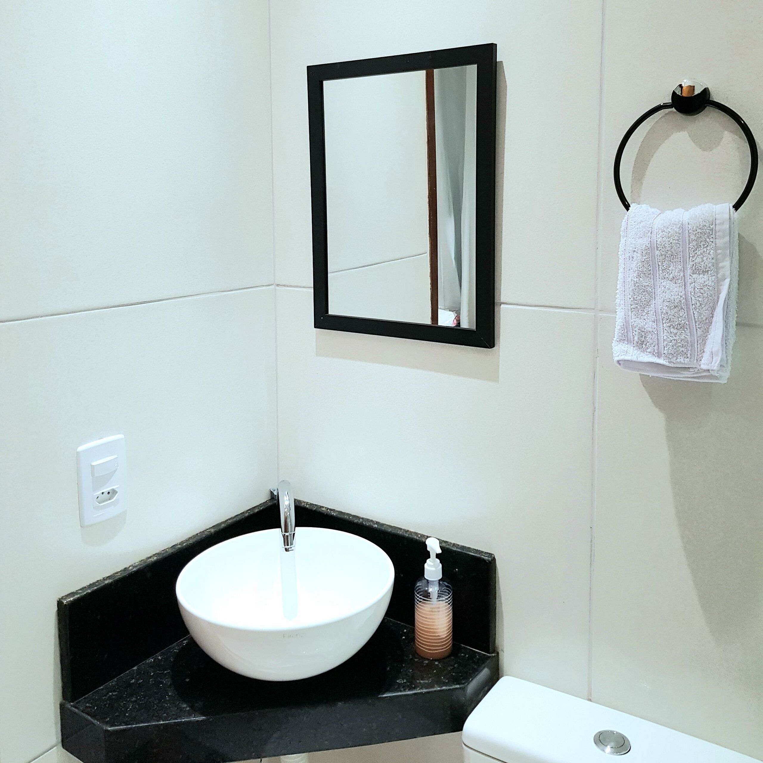 Een badkamer met een witte wastafel, een zwart aanrecht, een spiegel, een handdoekhouder en een toilet.