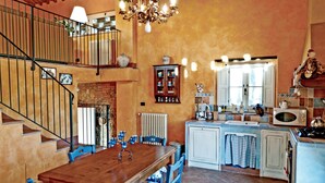 A spacious kitchen with a wooden dining table, blue chairs, and a staircase leading to an upper level. - Stunning home in Montelupo Fiorentino (Montelupo Fiorentino)