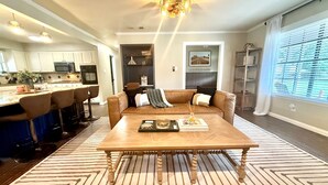 A modern living room with a wooden coffee table, a brown leather sofa, and a kitchen in the background. - Summer Oasis - Pool and Hot Tub, Private Backyard (Keller)