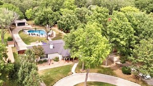 A residential area with a swimming pool, a house, and surrounding trees. - Summer Oasis - Pool and Hot Tub, Private Backyard (Keller)