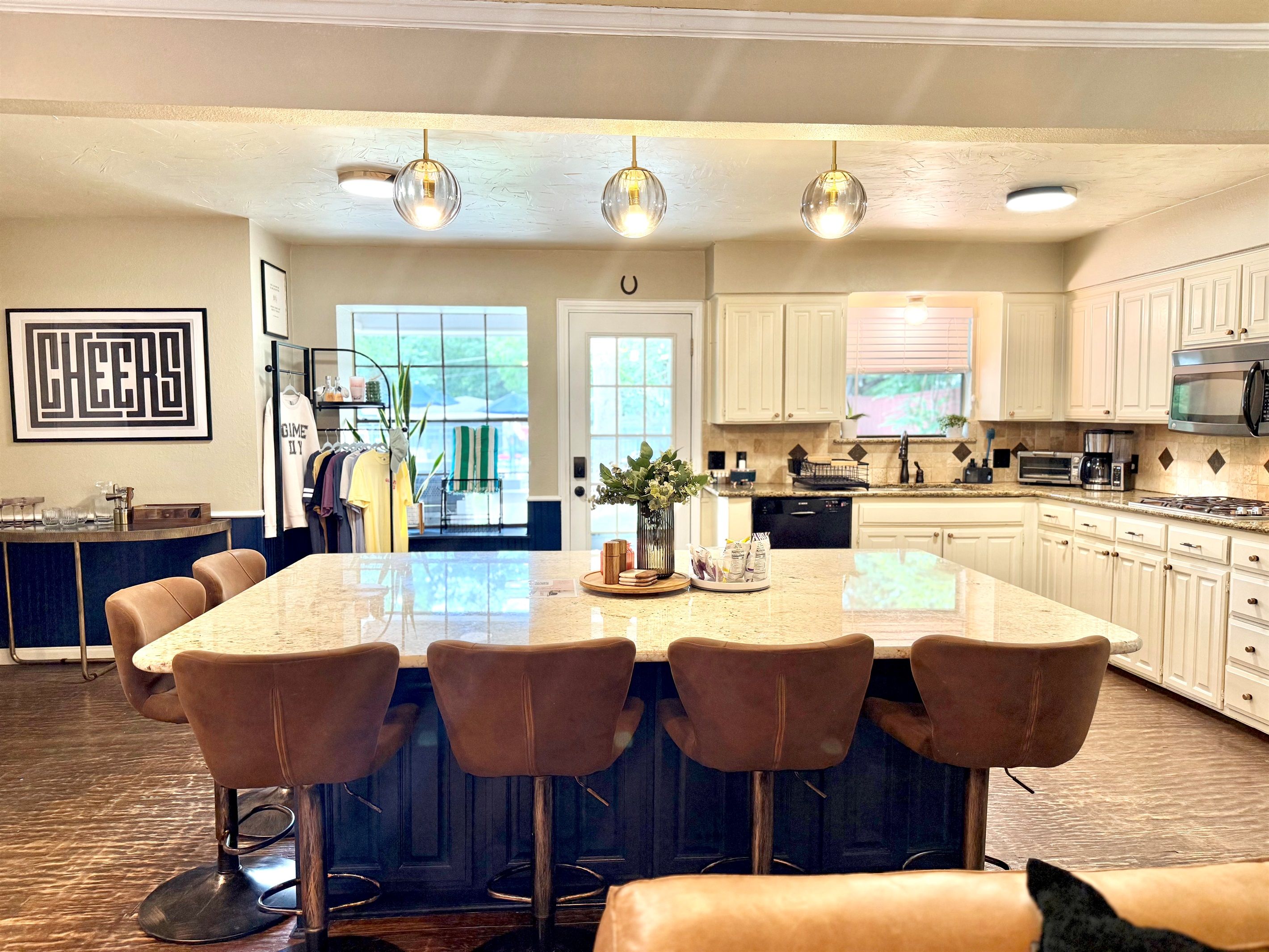 A modern kitchen with a large island, bar stools, and a view to the outdoors.