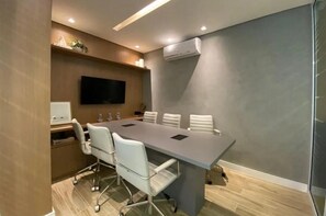 Conference room with a long table, flat-screen TV, and whiteboard.