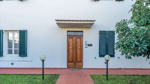 A building with a wooden double door, green shutters, and a tiled roof. - Appartamento Camilla - Affitti Brevi Italia (Lucca)