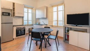 A compact kitchen with a dining area, a built-in TV, and a microwave. - Appartamento Camilla - Affitti Brevi Italia (Lucca)