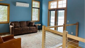 A room with a brown leather sofa, a small round table, and a wooden railing. - Little cabin (Rhinelander)
