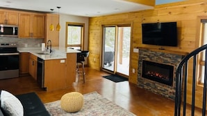 A modern kitchen with wooden cabinets, a central island, and a built-in oven. - Little cabin (Rhinelander)