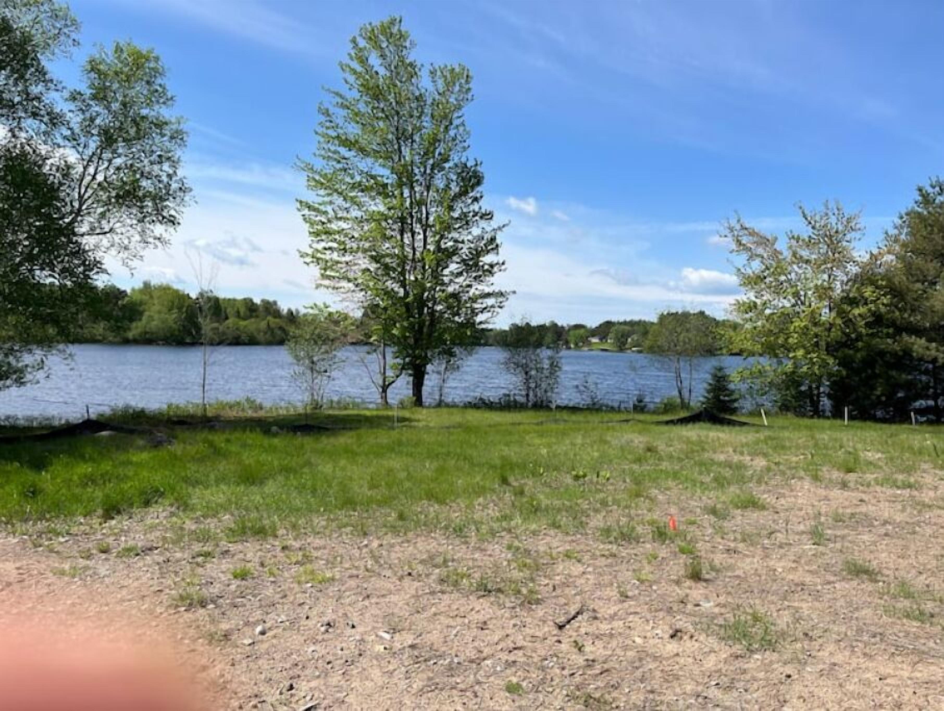 A lakeside view with trees and a grassy area.