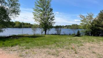 A lakeside view with trees and a grassy area.