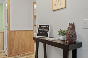 A reception desk with a welcome sign, a potted plant, and a decorative vase. - Elk Park Retreat - A Comfy & Stylish Mt. Hood Cabin - Hot Tub, Dogs OK (Mount Hood Village)