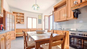 A kitchen with wooden cabinets, a dining table with chairs, a stove, and a hanging light fixture. - 2 bedroom cozy home in Varese Ligure (Varese Ligure)