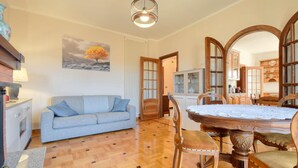 A cozy living room with a sofa, a dining table with chairs, a wooden cabinet, and a painting on the wall. - 2 bedroom cozy home in Varese Ligure (Varese Ligure)