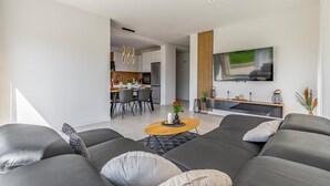 A modern living room with a grey sofa set, a wooden coffee table, and a flat-screen TV mounted on the wall. - 2 bedroom gorgeous apartment in Pula (Pula)