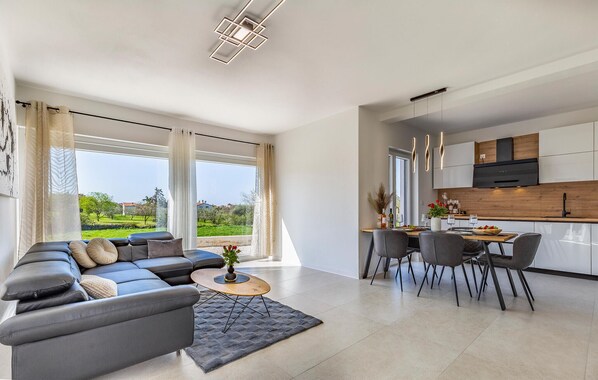 A modern living room with a sofa, a coffee table, and a dining area with chairs and a table.