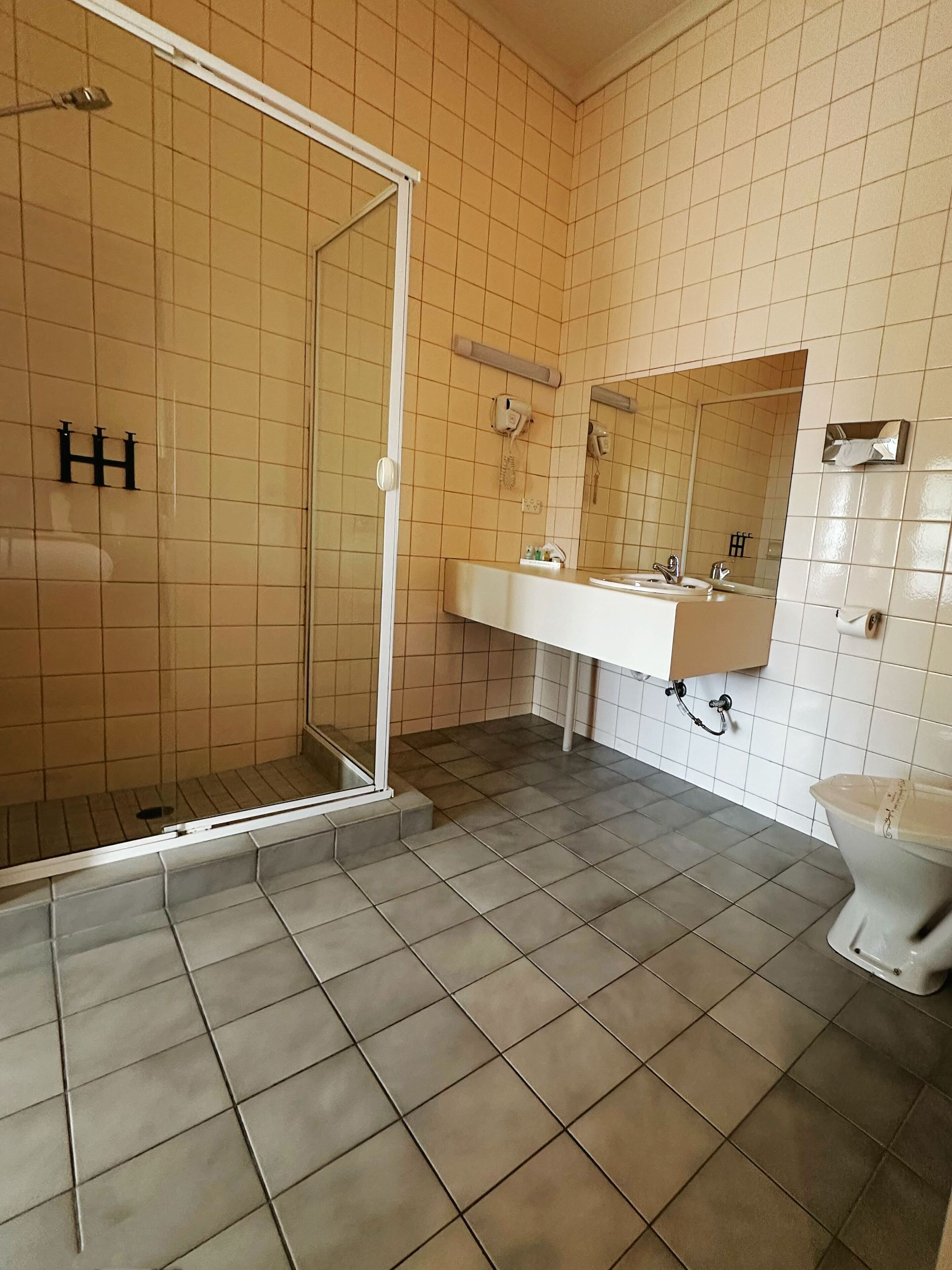 Un baño con cabina de ducha de vidrio, un lavabo blanco con espejo y un inodoro.