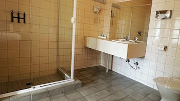 Un baño con cabina de ducha de vidrio, un lavabo blanco con espejo y un inodoro.