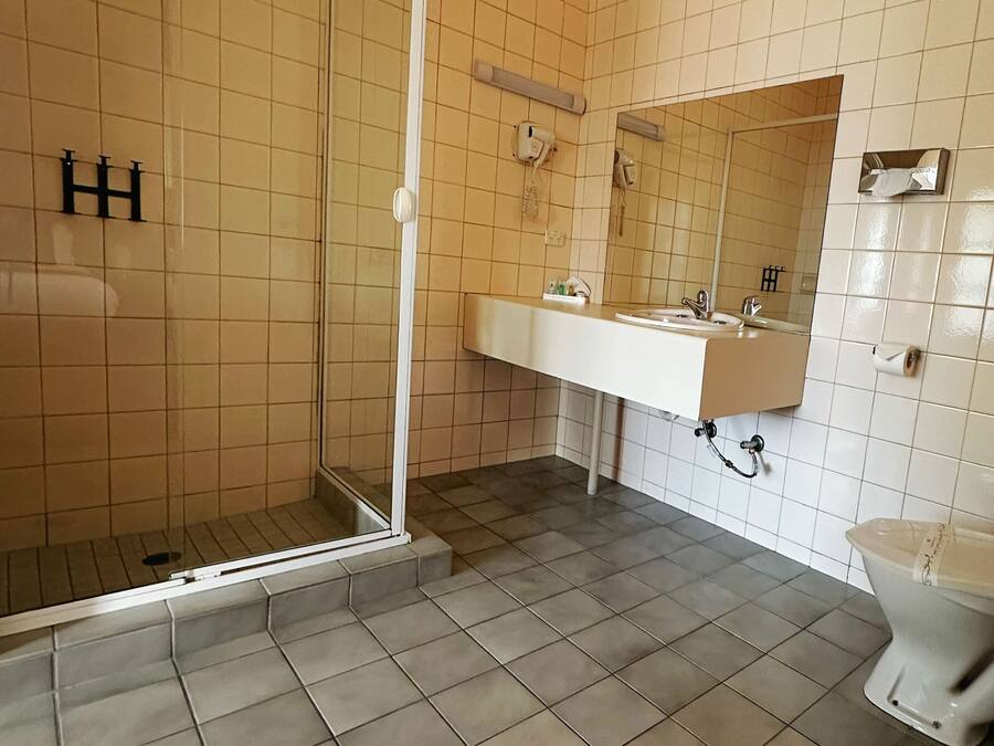 Un baño con cabina de ducha de vidrio, un lavabo blanco con espejo y un inodoro.
