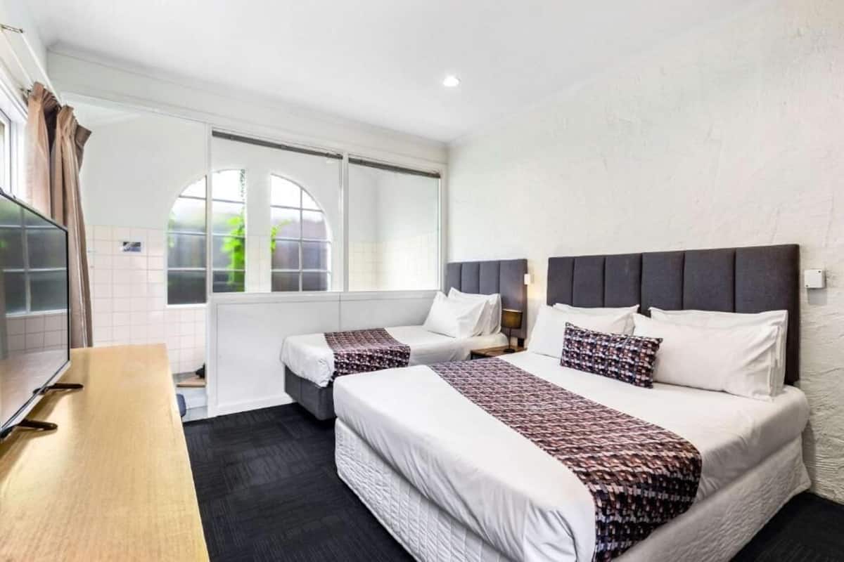 A hotel room with two beds, a TV, and a large window.