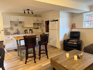Una cocina moderna con armarios blancos, una isla central y un comedor con dos sillas.