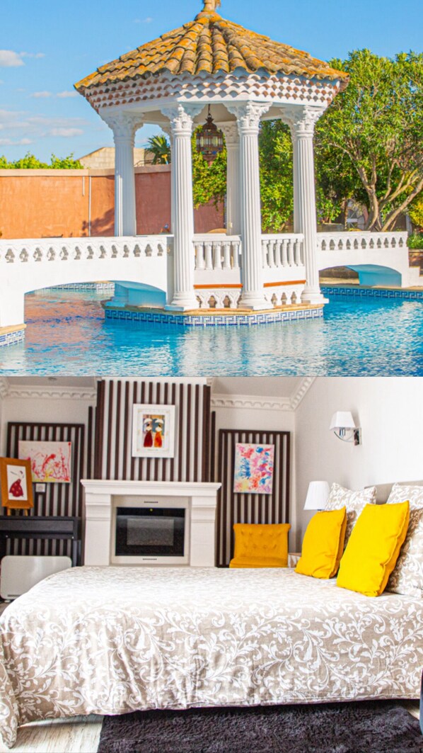 A pool with a gazebo, a fireplace, and a bed with yellow pillows.