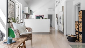 A modern kitchen with a central island, a dining area with a wicker chair, and a living space with a fireplace. - Cozy home in Vejby with sauna (Vejby)