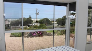 Ein Zimmer mit großen Fenstern und Blick auf einen Garten und das Meer.