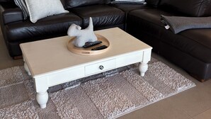 Ein Wohnzimmer mit einem schwarzen Leder-Modulsofa, einem weißen Couchtisch und einem beigen Teppich.