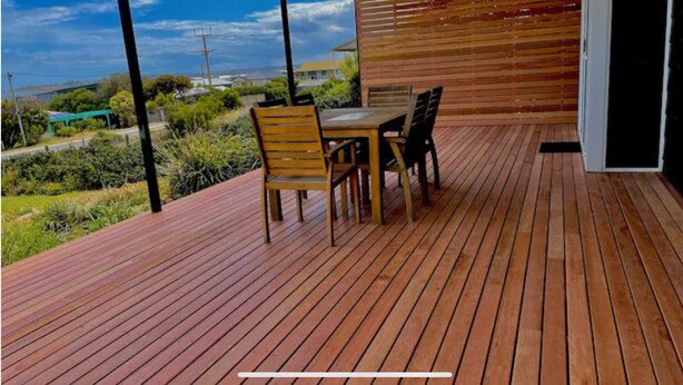 Eine Holzterrasse mit Tisch und Stühlen mit Blick auf eine Wohngegend.