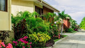 Una hilera de casas con jardines exuberantes y una acera pavimentada.