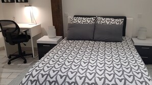 Un dormitorio con cama, escritorio y silla.