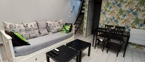 A living room with a sofa, a coffee table, and a dining area with chairs and a table.