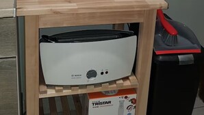 Una encimera de cocina con cafetera, hervidor y licuadora sobre un soporte de madera.