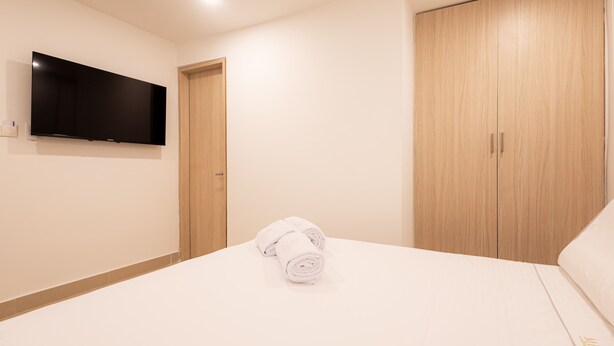 Una camera d'albergo con un letto, una TV a parete e un armadio in legno.