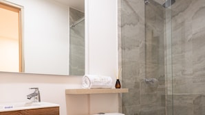 Un bagno moderno con cabina doccia in vetro, un water bianco e un mobile lavabo in legno.