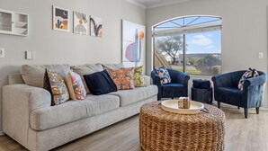 A living room with a sofa, two armchairs, a coffee table, and artwork on the walls. - Kid Friendly 2-bedroom condo in Scottsdale with Pool, Hottub, fitness room, WiFi (Scottsdale)